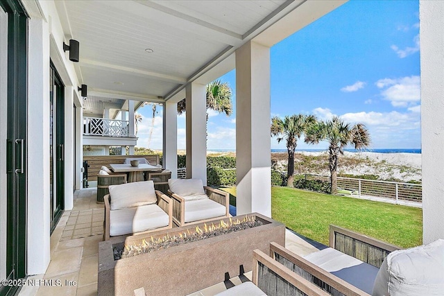 view of patio / terrace with a balcony, fence, and an outdoor living space with a fire pit