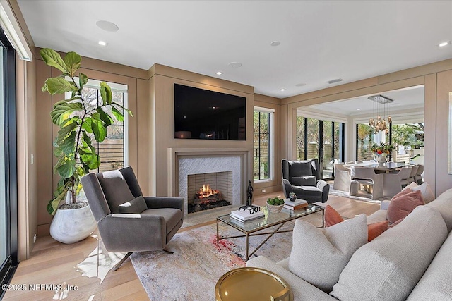 living area with visible vents, wood finished floors, a high end fireplace, and recessed lighting