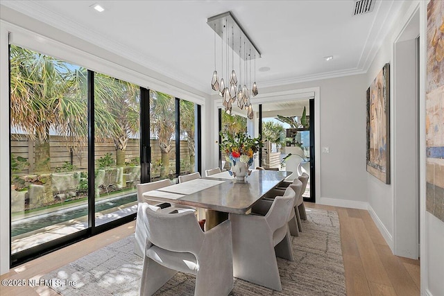 dining space featuring light wood-style floors, visible vents, crown molding, and baseboards