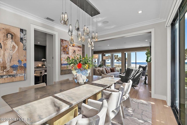 dining room featuring baseboards, wood finished floors, visible vents, and crown molding