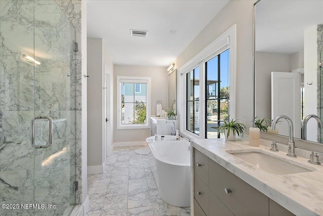 full bathroom featuring marble finish floor, a marble finish shower, visible vents, a freestanding tub, and baseboards