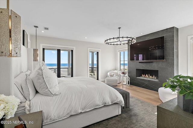 bedroom with multiple windows, a fireplace, wood finished floors, and visible vents