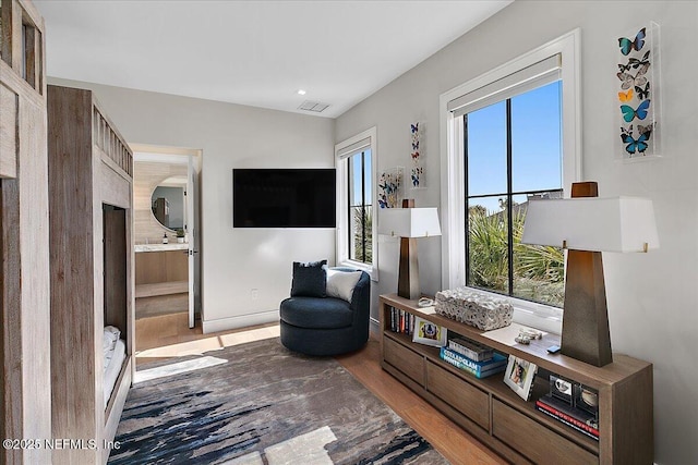 sitting room with baseboards, visible vents, and wood finished floors