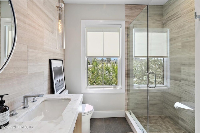 bathroom with toilet, a stall shower, vanity, tile patterned flooring, and baseboards