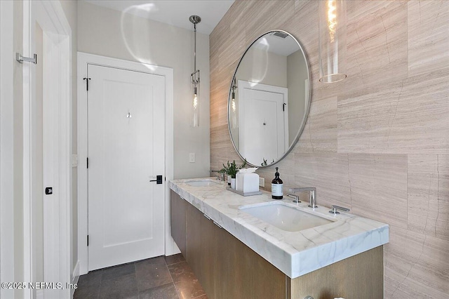 bathroom with a sink, tile walls, and double vanity