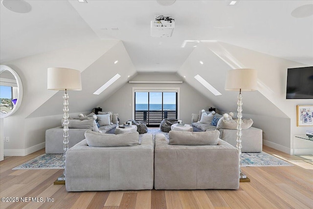 living room with lofted ceiling with skylight, baseboards, and wood finished floors