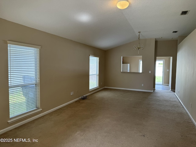 carpeted empty room with baseboards, visible vents, vaulted ceiling, and a wealth of natural light