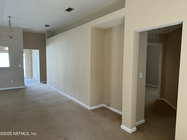 carpeted empty room with baseboards, visible vents, and a textured ceiling