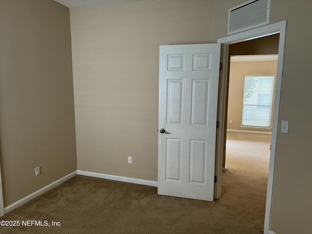 unfurnished room featuring carpet, visible vents, and baseboards