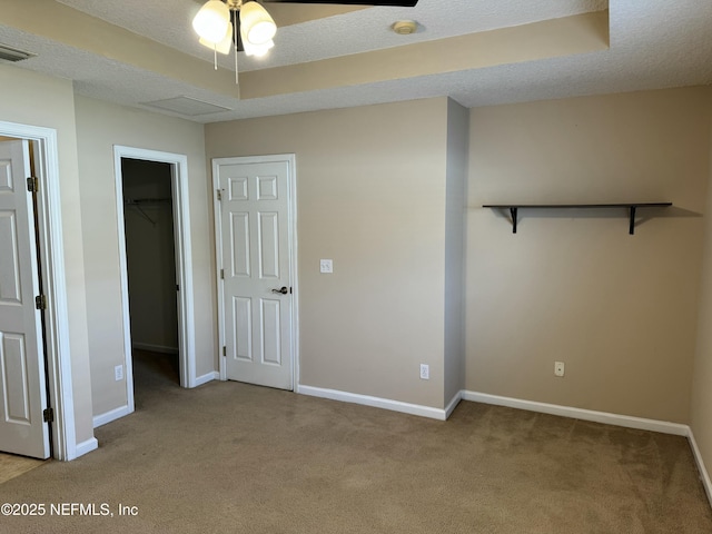 unfurnished bedroom with light carpet, a spacious closet, and a textured ceiling