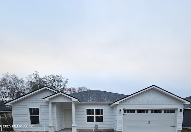 single story home featuring a shingled roof, driveway, and an attached garage