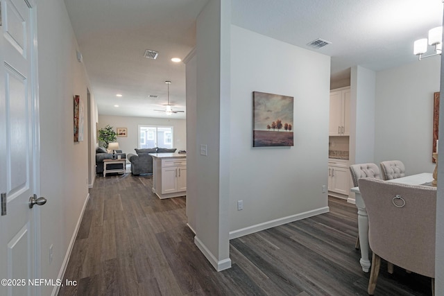 corridor featuring dark wood-style floors, baseboards, visible vents, and recessed lighting