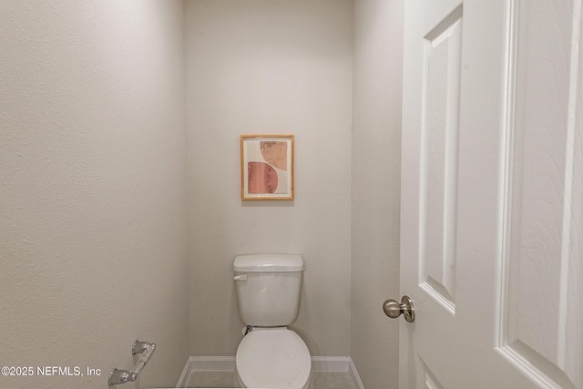 bathroom featuring baseboards and toilet