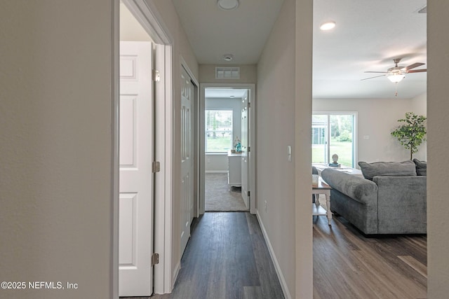 hallway with plenty of natural light, wood finished floors, visible vents, and baseboards