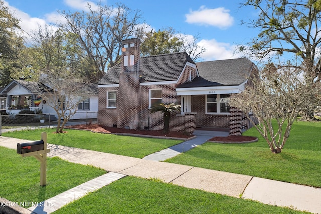 view of front of house with brick siding, roof with shingles, a front yard, and fence