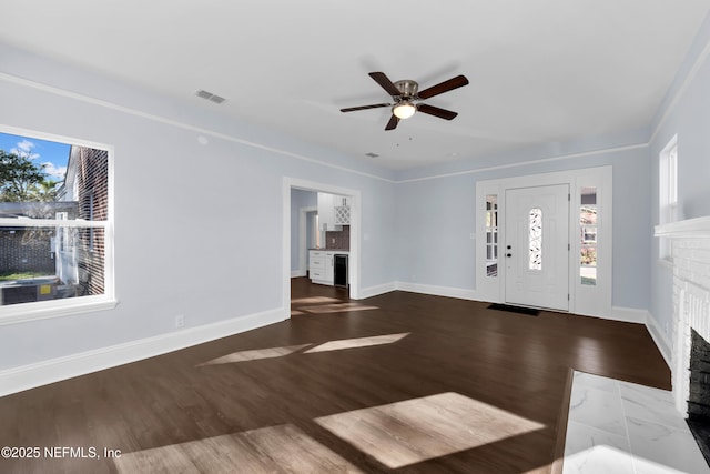 entryway featuring visible vents, a fireplace, baseboards, and wood finished floors