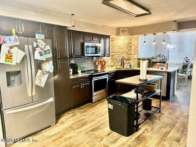 kitchen with light countertops, backsplash, light wood-style flooring, appliances with stainless steel finishes, and dark brown cabinets