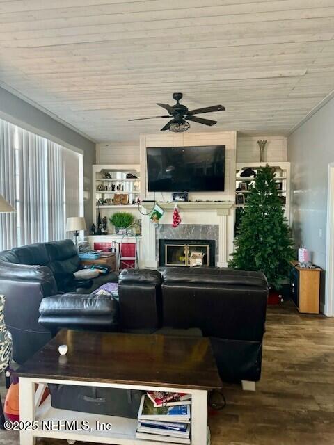 living room featuring a ceiling fan, a high end fireplace, and wood finished floors