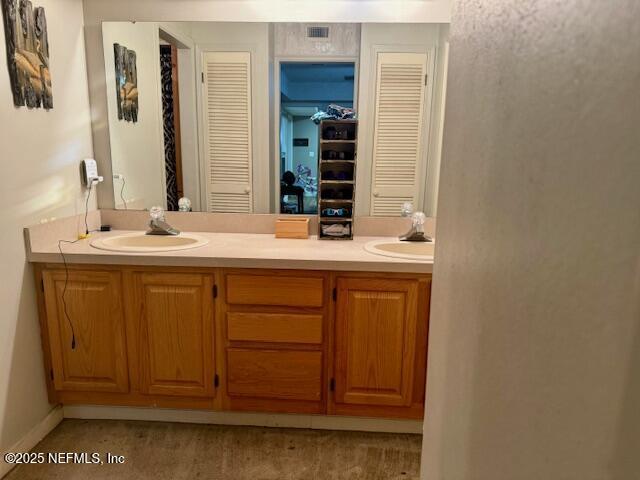 bathroom with double vanity, a closet, and a sink