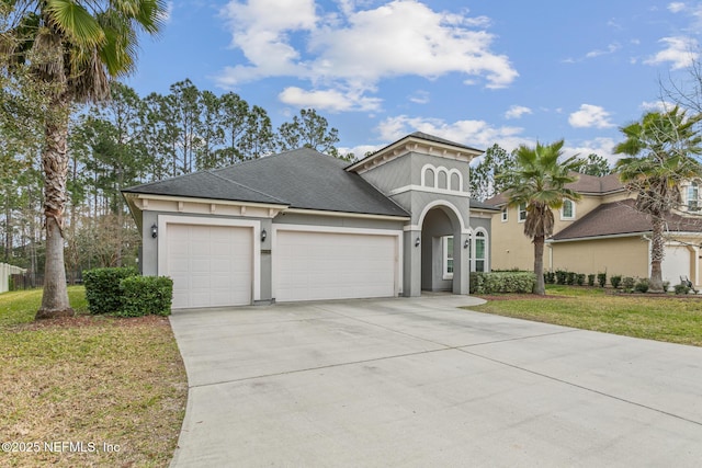 view of front of home with a garage, driveway, a front yard, and stucco siding