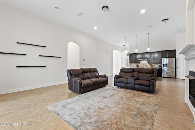 living area with arched walkways, crown molding, recessed lighting, and baseboards