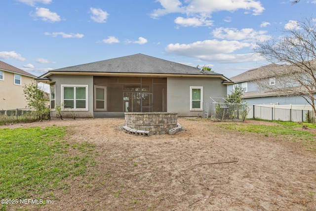 rear view of house with a shingled roof, a sunroom, fence, and stucco siding