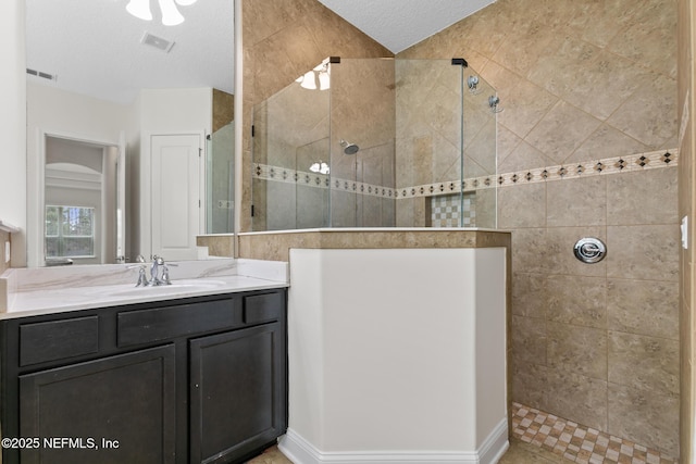 bathroom with visible vents, vanity, a textured ceiling, and a walk in shower