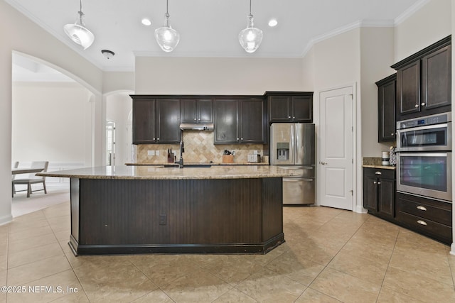 kitchen featuring arched walkways, stainless steel appliances, ornamental molding, a sink, and light stone countertops