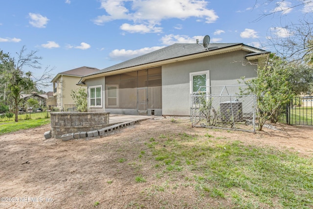 rear view of property with fence, a sunroom, and stucco siding