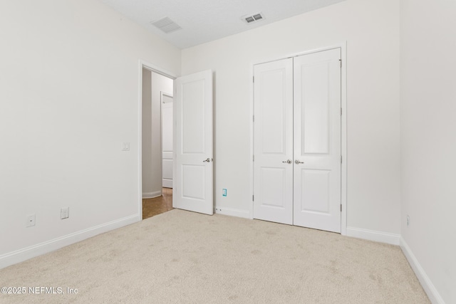 unfurnished bedroom with a closet, carpet flooring, visible vents, and baseboards