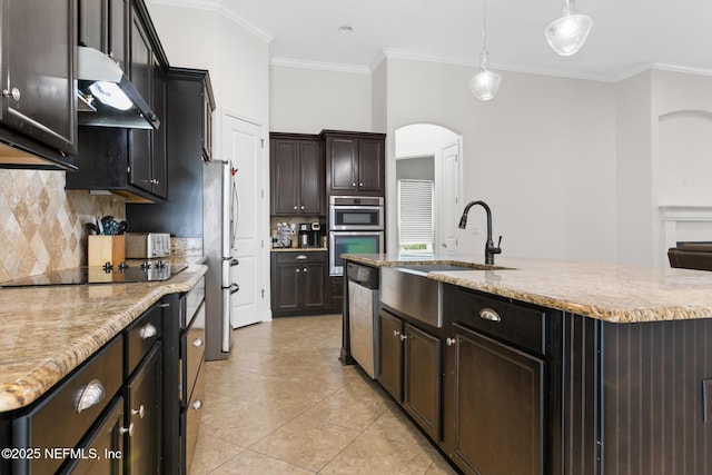 kitchen with arched walkways, crown molding, hanging light fixtures, appliances with stainless steel finishes, and under cabinet range hood