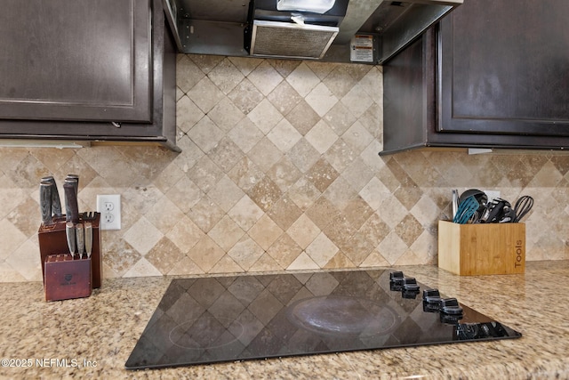 kitchen featuring dark brown cabinets, black electric stovetop, ventilation hood, and decorative backsplash