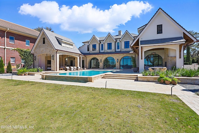 rear view of house with a patio area, an outdoor pool, and a yard