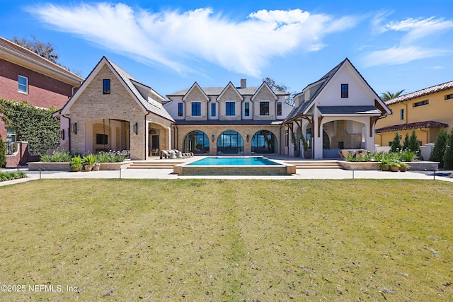 back of property with an outdoor pool and a yard