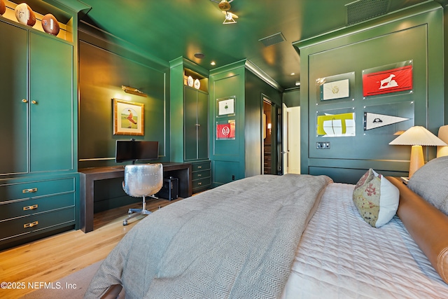 bedroom featuring built in desk, wood finished floors, visible vents, and crown molding