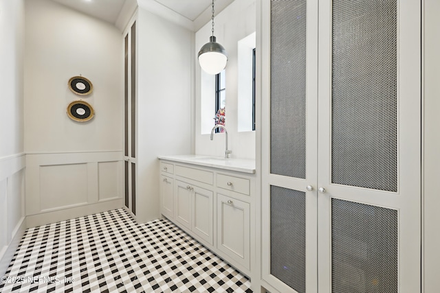 bathroom featuring wainscoting, a decorative wall, and vanity