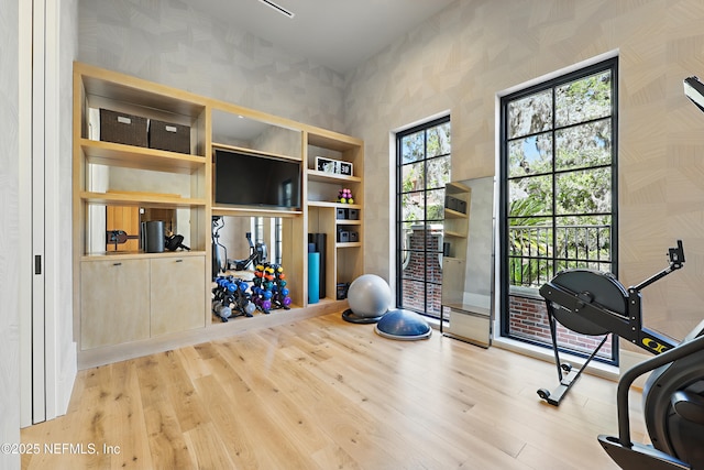 workout area with wood finished floors and wallpapered walls