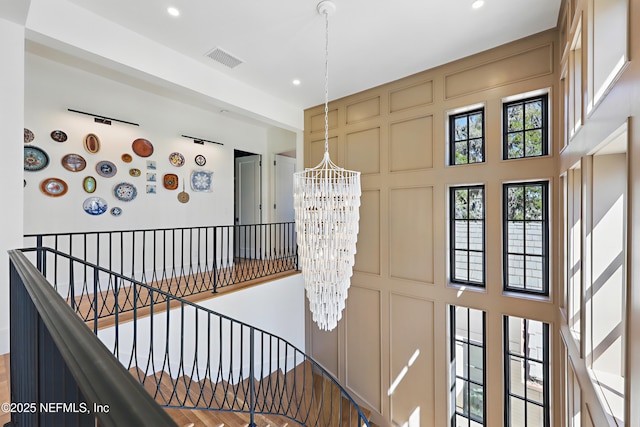 interior space featuring a decorative wall, recessed lighting, a high ceiling, visible vents, and an inviting chandelier