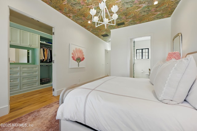 bedroom with an ornate ceiling, a closet, visible vents, light wood-style flooring, and an inviting chandelier