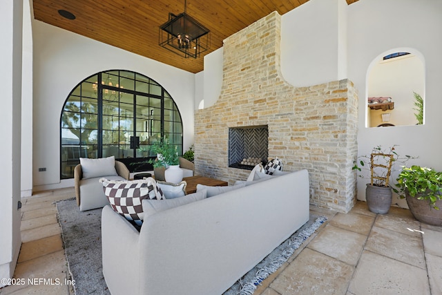 living room with wooden ceiling, an outdoor brick fireplace, high vaulted ceiling, and an inviting chandelier