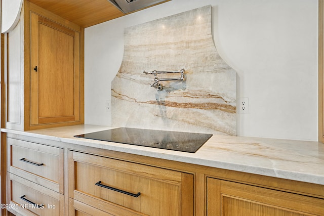 room details featuring light stone counters and black electric cooktop