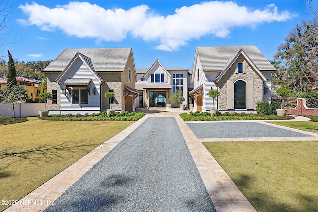 view of front facade featuring stone siding, fence, and a front yard