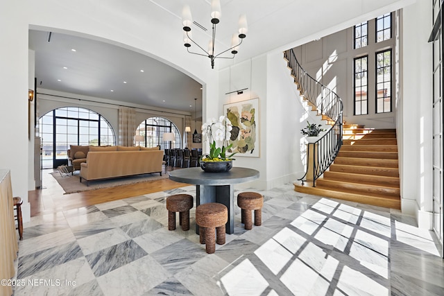 entryway featuring stairs, french doors, arched walkways, and an inviting chandelier