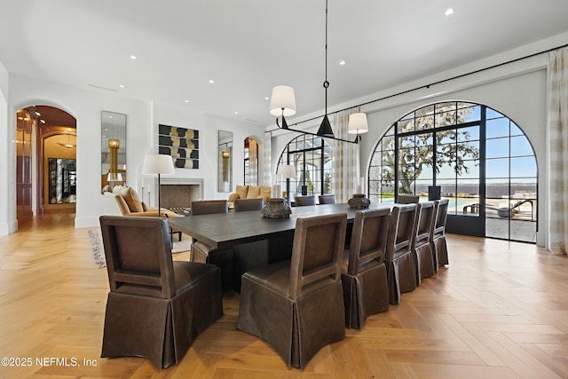 dining room with arched walkways, a fireplace, and recessed lighting