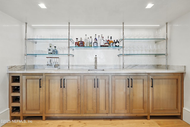 bar featuring light wood-style floors, a sink, and wet bar