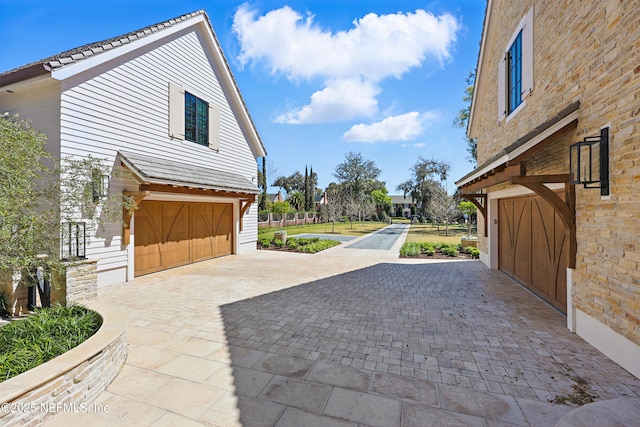 view of side of home with a garage and decorative driveway