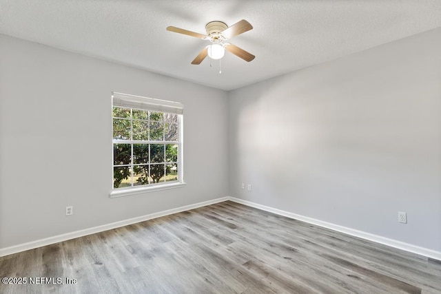 unfurnished room with ceiling fan, a textured ceiling, baseboards, and wood finished floors