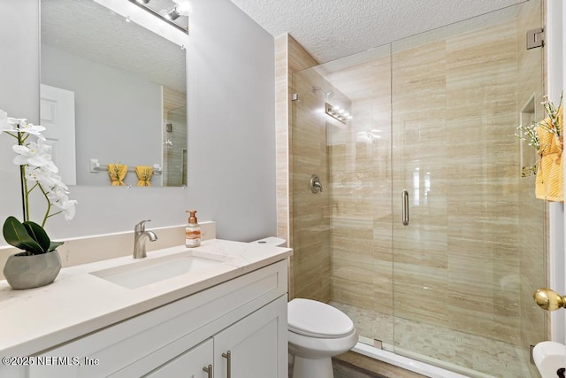 full bathroom featuring a textured ceiling, vanity, a shower stall, and toilet