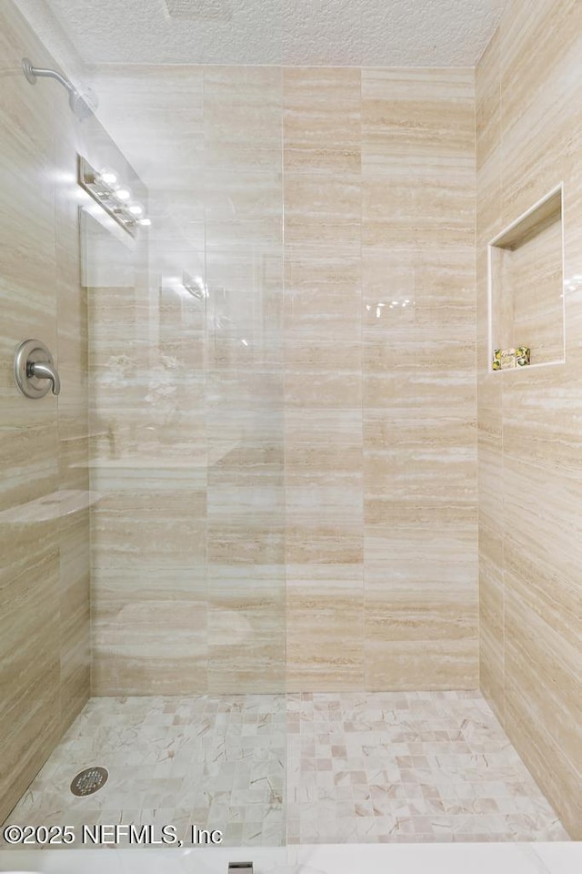 bathroom with a tile shower and a textured ceiling