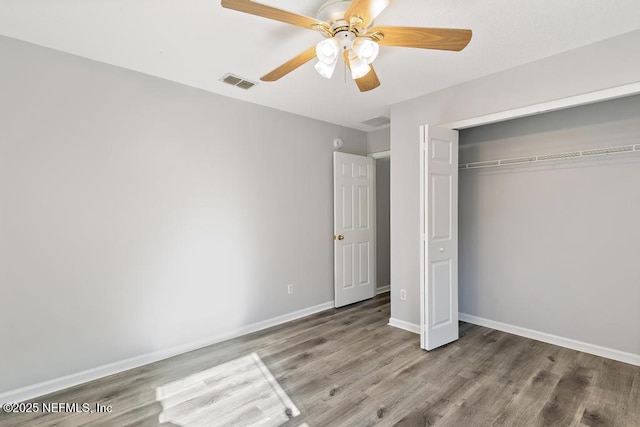 unfurnished bedroom featuring a closet, visible vents, baseboards, and wood finished floors